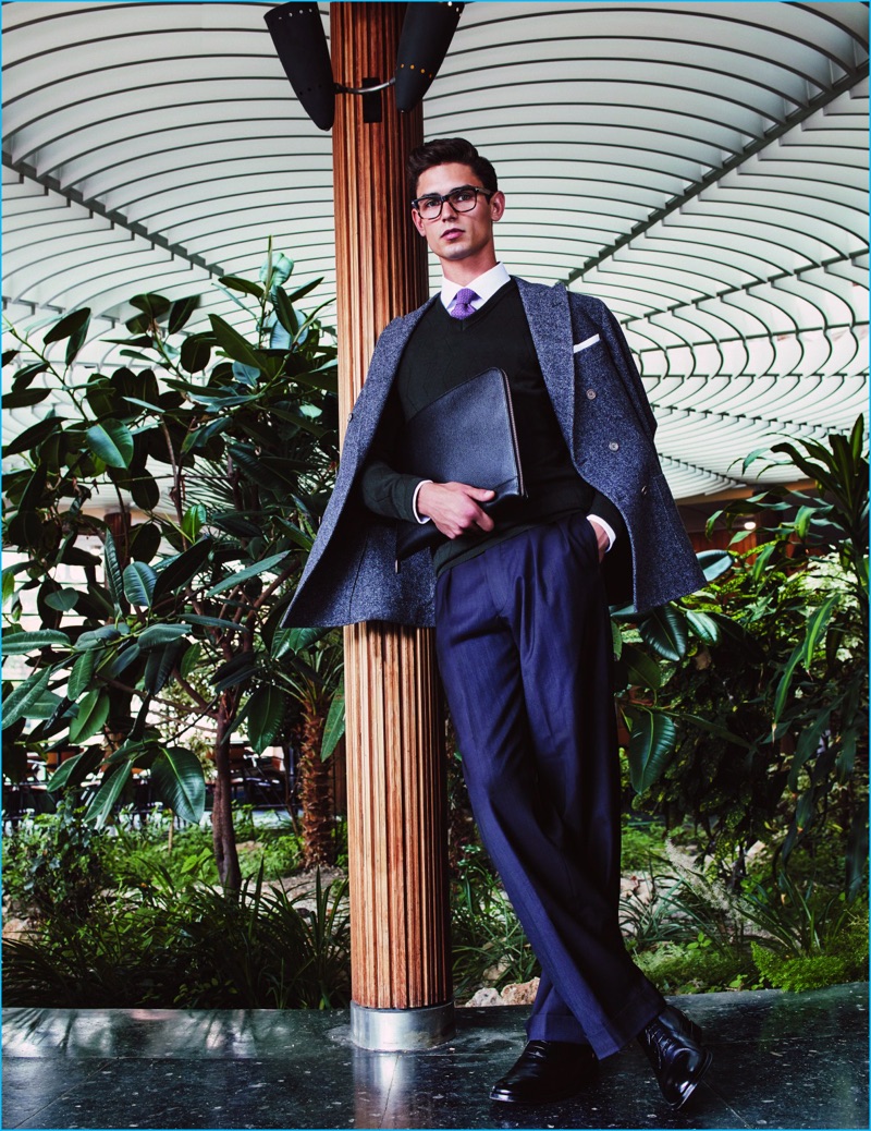 Standing tall, Arthur Gosse dons a Brunello Cucinelli double-breasted jacket with a Z Zegna sweater, Ermenegildo Zegna trousers, Givenchy glasses, and a Hermes tie. Arthur also sports shoes and a leather portfolio from Boss by Hugo Boss.