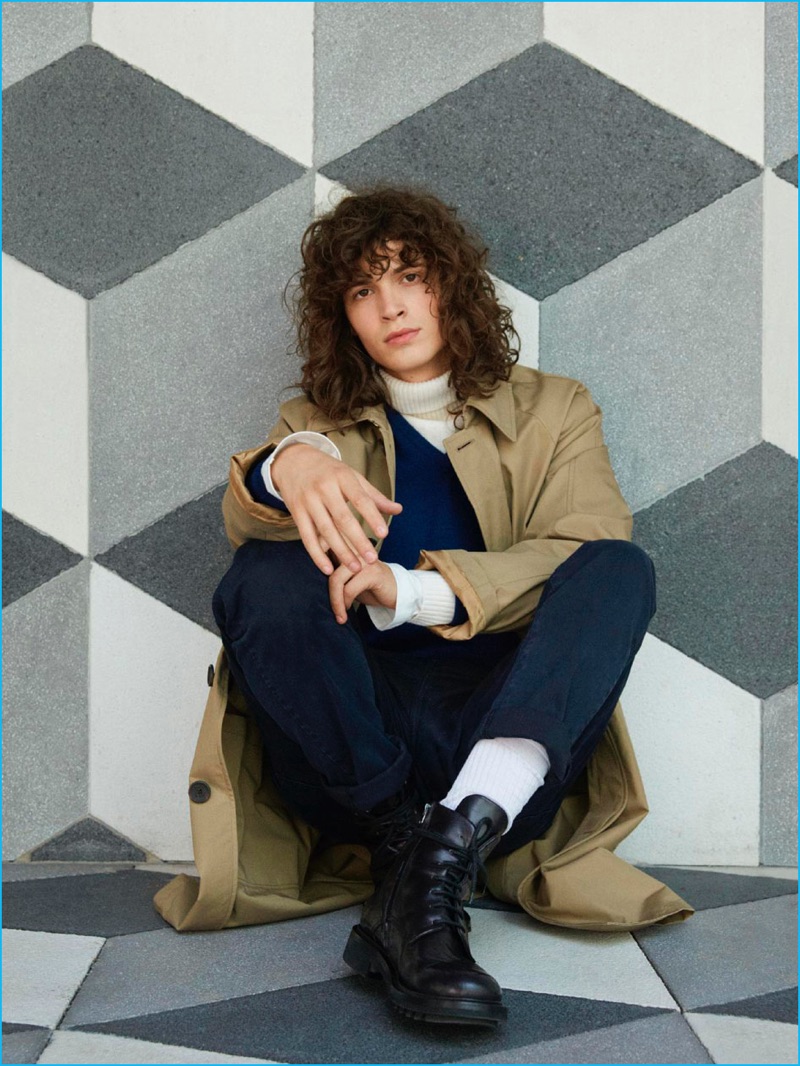 Model George Culafic sports a Sealup trench coat, Malo v-neck sweater, Gant turtleneck, Acne Studios long-sleeve tee, Siviglia pants, and Pal Zileri boots.