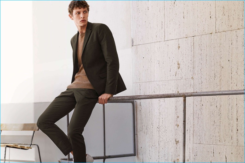 Embracing a smart fall look, Tim Schuhmacher models a cotton suit, wool-blend sweater, and white leather sneakers from H&M.