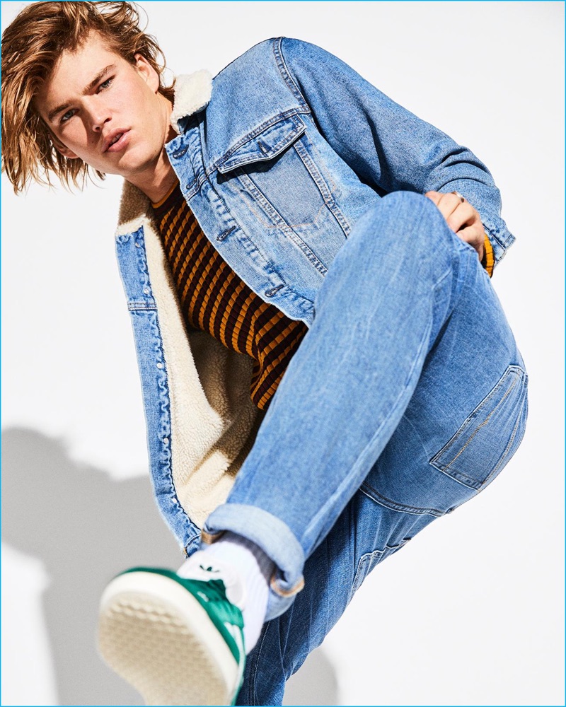 Doubling down on denim, Jordan Barrett wears a New Look denim jacket with Levi's jeans. The leading model also sports a striped sweater from Just Cavalli with Adidas sneakers.