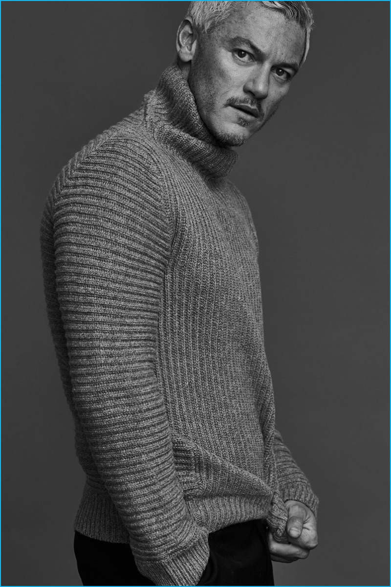 Embracing a chic image, Luke Evans wears a ribbed wool turtleneck sweater from Acne Studios with Balenciaga trousers.