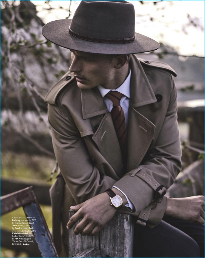 Australian model Nathaniel Visser dons a Burberry trench coat and Thomas Pink shirt with a Canali tie, Calvin Klein White Label trousers, a Cartier watch, and RM Williams felt fedora.