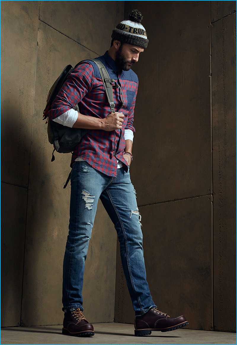Going casual with LE 31, Noah Mills wears a chambray-block plaid shirt and mossy green beanie. The top model also sports Levi's distressed 511 denim jeans and Toms Ashland boots with a Jansport backpack.