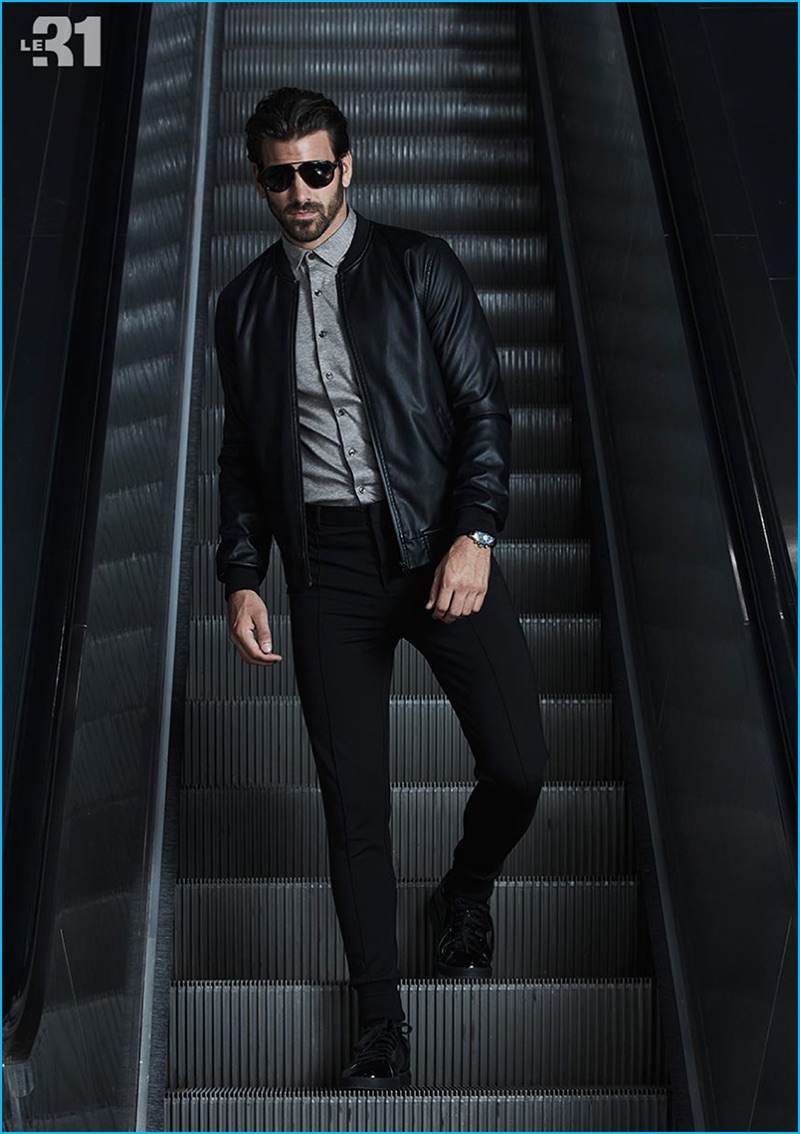 Embracing cool travel style, Nyle DiMarco wears a faux leather bomber jacket, cotton shirt, and jersey traveler pants from LE 31 with Carrera signature aviator sunglasses from Simons.