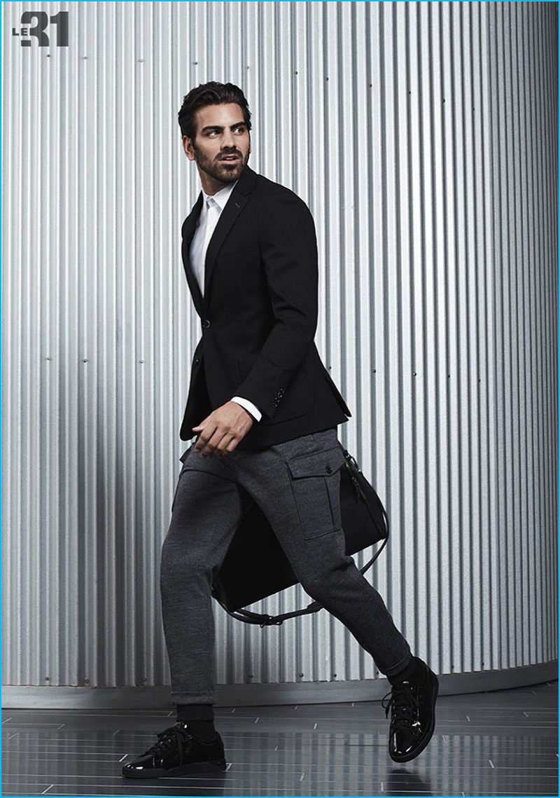 On the move, Nyle DiMarco models a LE 31 solid traveler shirt and chambray wool cargo joggers with a Bosco semi-slim fit jacket, Matt & Nat weekend bag, and HUGO by Hugo Boss sneakers from Simons.