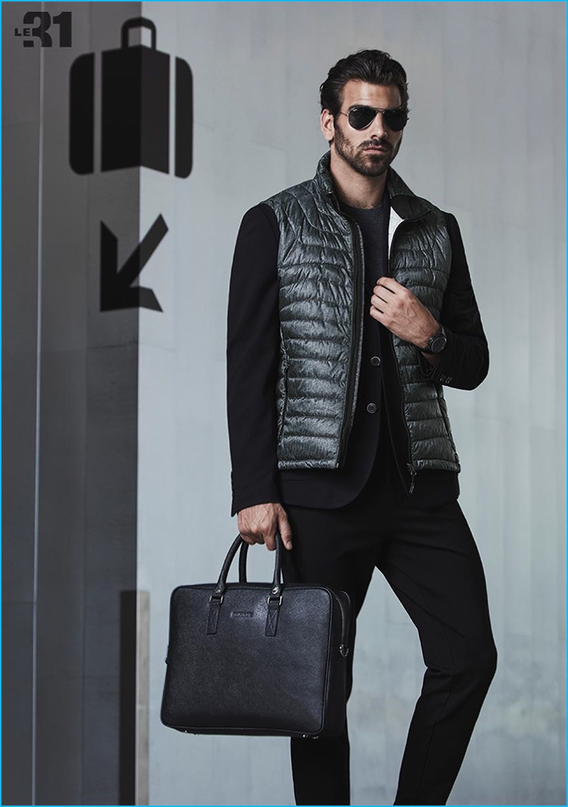 Standing out in contemporary travel style, Nyle DiMarco models a LE 31 t-shirt, Projek Raw quilted vest, and Bosco semi-slim fit jacket with Ray-Ban aviator sunglasses and a Rudsak leather briefcase from Simons.