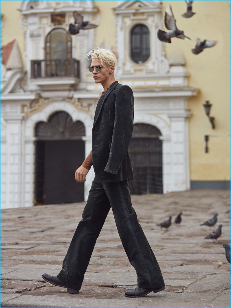 A svelte figure, Oliver Stummvoll rocks a Bottega Veneta suit with a Ralph Lauren sweater, Ray-Ban sunglasses, and Hugo Boss shoes.