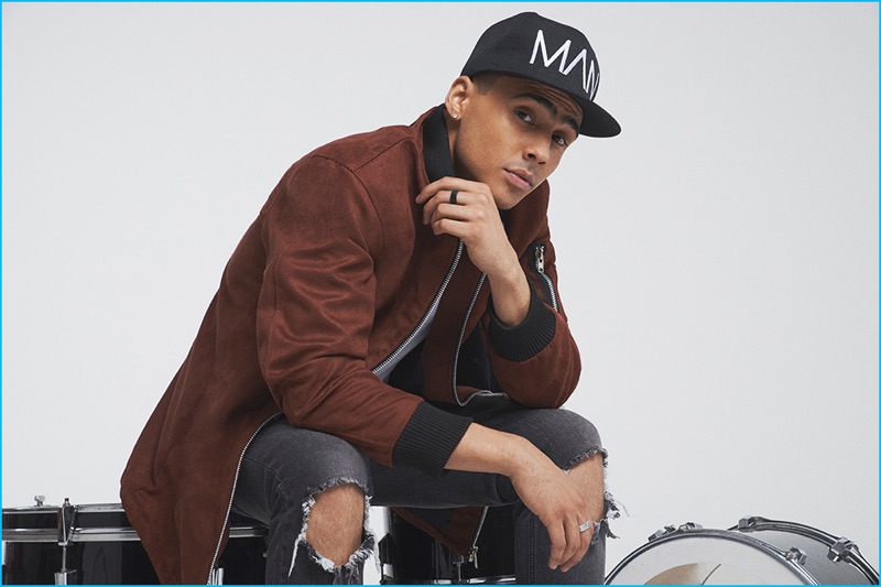 Quincy embraces an urban appeal in a longline bomber jacket, ripped jeans, and a cap from BoohooMan's fall-winter 2016 capsule collection.