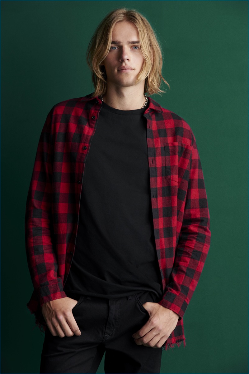 Front and center, Ton Heukels sports a red and black buffalo check shirt with a t-shirt and jeans from River Island.