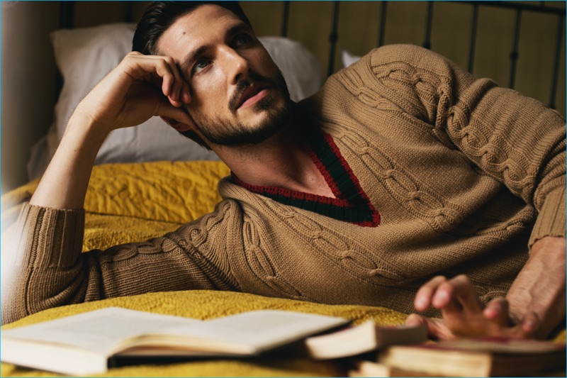 Relaxing in bed, Ryan Douglas sports a cable-knit v-neck sweater from Gucci.