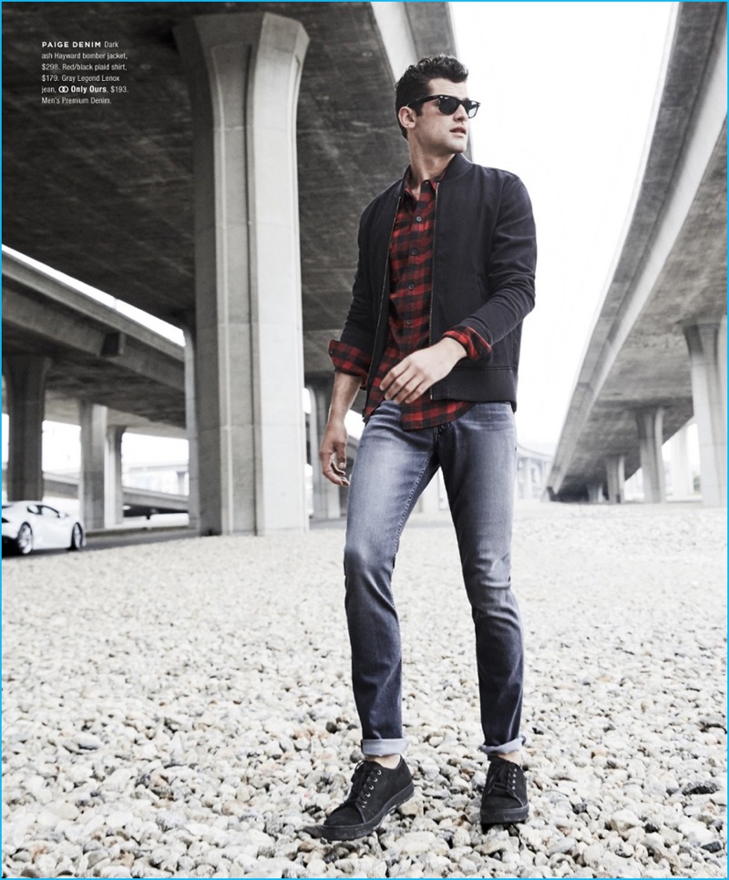 Channeling all-American style, Sean O'Pry wears a bomber jacket, plaid shirt, and denim jeans from Paige Denim.
