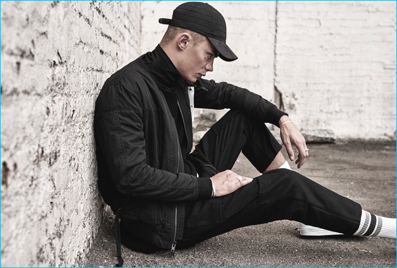 Czech model Simon Kotyk wears a black bomber jacket from the Stampd x United Arrows & Sons Purple Heart collection.