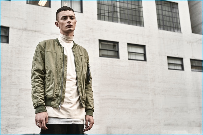 Simon Kotyk rocks a green bomber jacket from the Stampd x United Arrows & Sons Purple Heart collection.