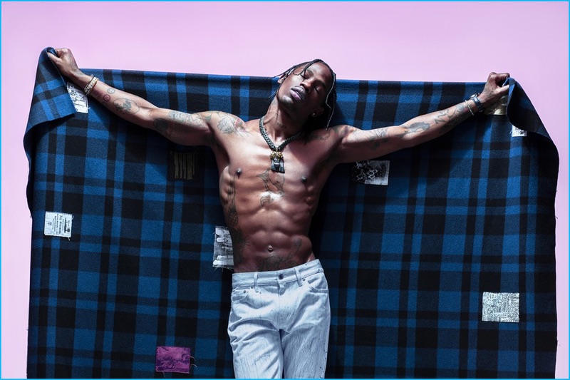 A shirtless Travis Scott flexes in Louis Vuitton jeans and a Raf Simons blanket for Paper magazine.