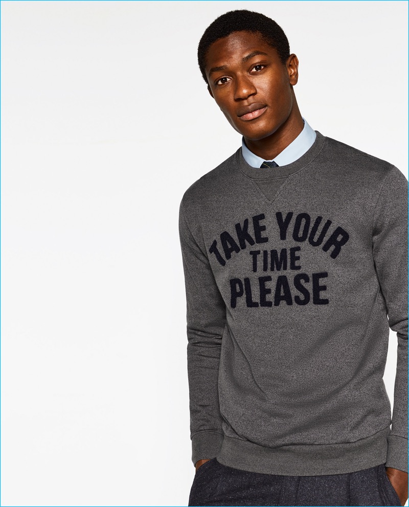 Embracing style with humor, Hamid Onifade wears a Take Your Time Please sweatshirt from Zara Man's College League collection.