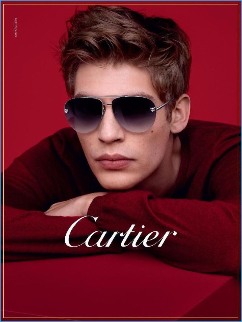 Posing against a red background, Baptiste Radufe sports Panthére de Cartier Aviators.