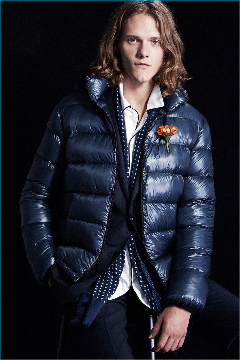 Juxtaposing aesthetics, Ryan Keating models a Herno puffer jacket with a navy suit, a Sleepy Jones pajama shirt, and polk dot scarf from Club Monaco.