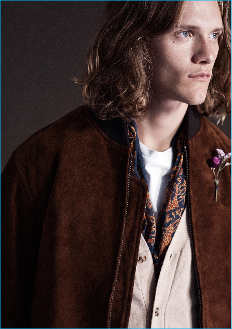 Ryan Keating layers in a wool cardigan, patterned scarf and Golden Bear bomber jacket from Club Monaco.
