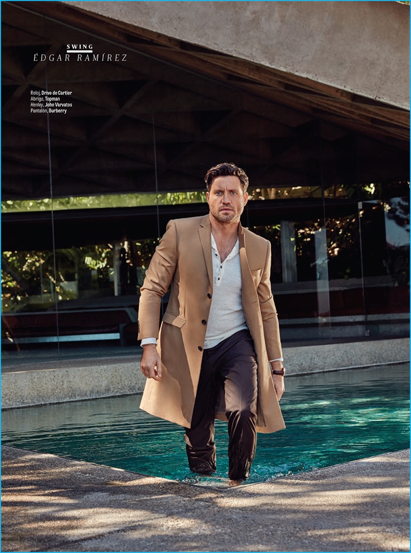 Appearing in a feature for GQ Latin America, Edgar Ramirez dons a single-breasted Topman coat with a John Varvatos henley and pleated Burberry trousers.