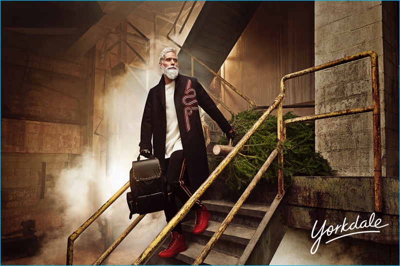 On the move, Fashion Santa sports a Dries Van Noten embroidered coat, Jimmy Choo red high top sneakers, a T by Alexander Wang pullover, and Palm Angels track pants. The jovial legend also carries a Burberry leather backpack.