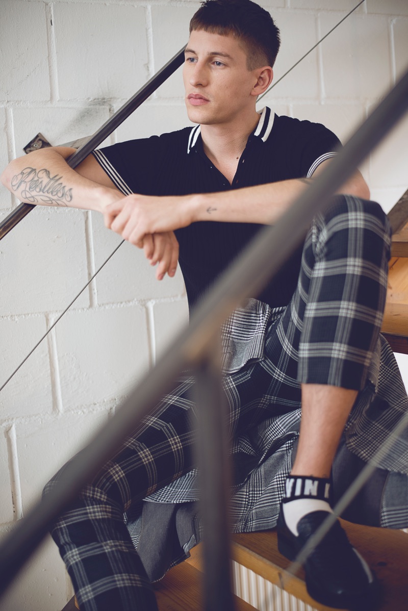 Sitting on the stars, Jannik models Noose & Monkey check trousers with Calvin Klein socks, as well as a knit polo, blazer, and shoes by Zara Man.