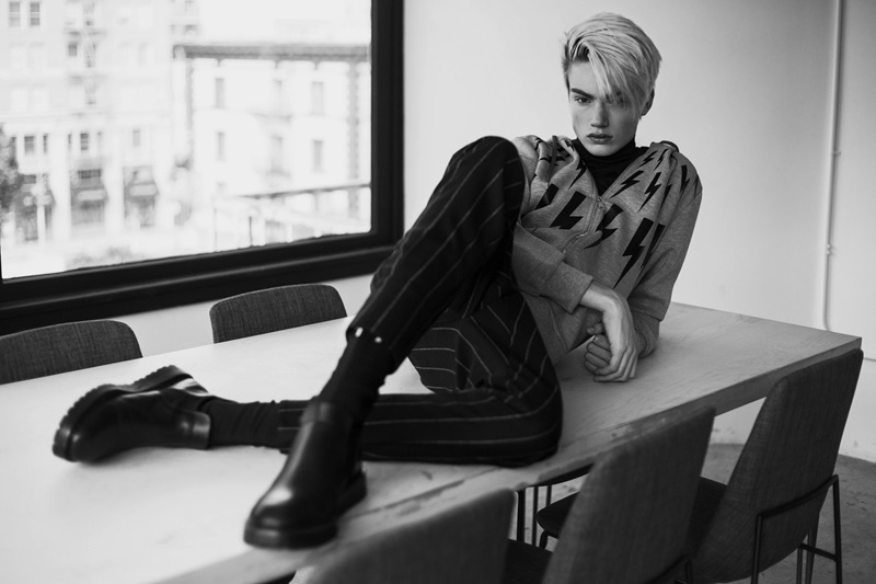 Elijah is the center of attention as he models a Neil Barrett sweatshirt, Jil Sander turtleneck, Vivienne Westwood trousers, and Kris Van Assche boots.