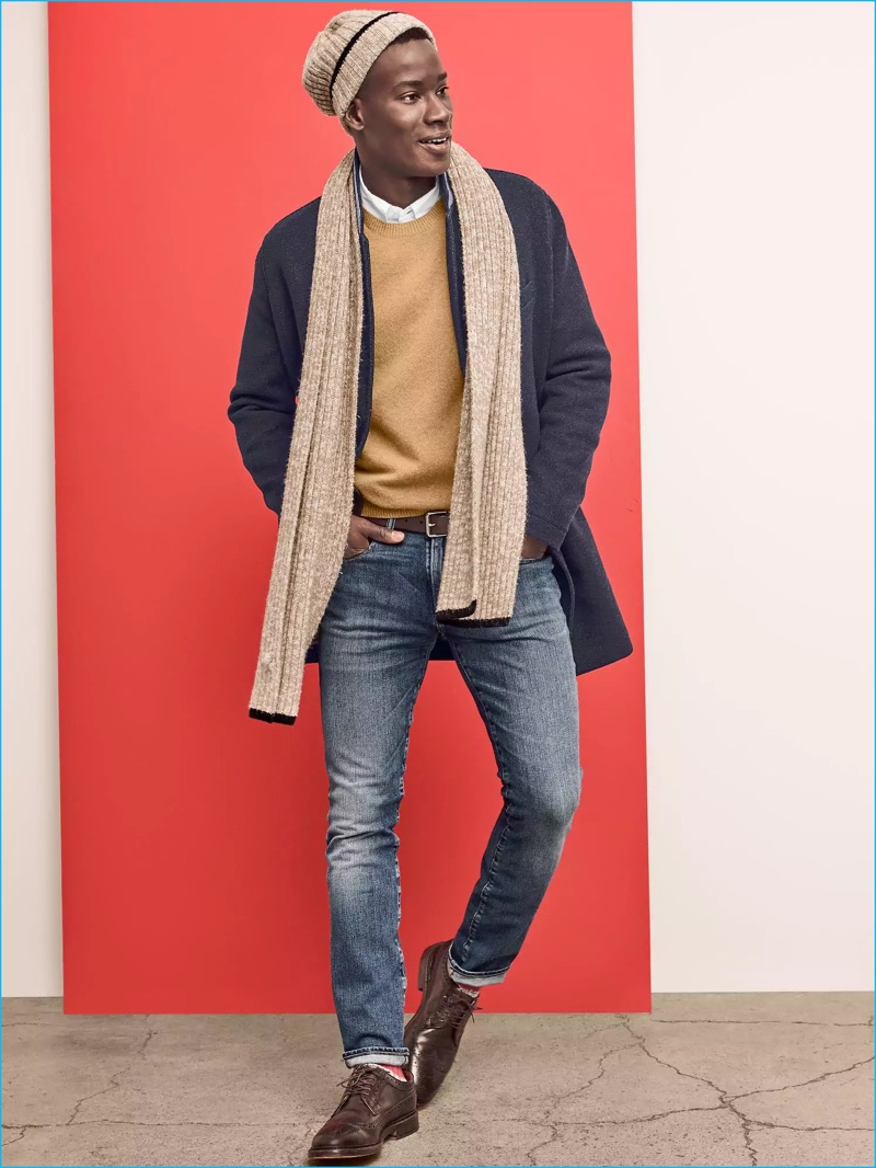 David Agbodji sports a wool coat and camel toned sweater from Gap. The top model also dons distressed denim jeans with a match scarf and knit beanie.