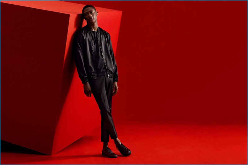 Model Hamid Onifade models a black bomber jacket, cotton t-shirt, cropped trousers, and sneakers from H&M's Black Friday collection.