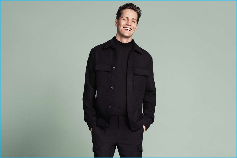 All smiles, Peter Bruder models a wool-blend shirt jacket, mock turtleneck sweater, and wool-blend cargo pants.