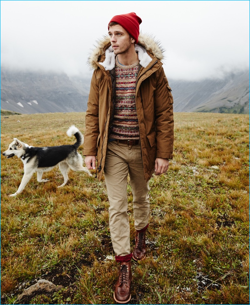 Venturing outdoors, Benjamin Eidem wears J.Crew's Nordic down parka with a fair isle sweater. The top model also sports a Wallace & Barnes indigo pocket t-shirt, 770 chino cabin pants, a red knit beanie, and Kenton leather pacer boots.