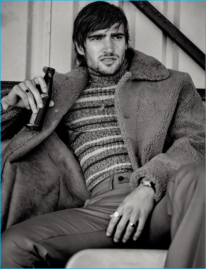 Luke Day outfits Jack Tyerman in a Tiger of Sweden shearling coat with a Roberto Cavalli striped sweater and wool trousers.