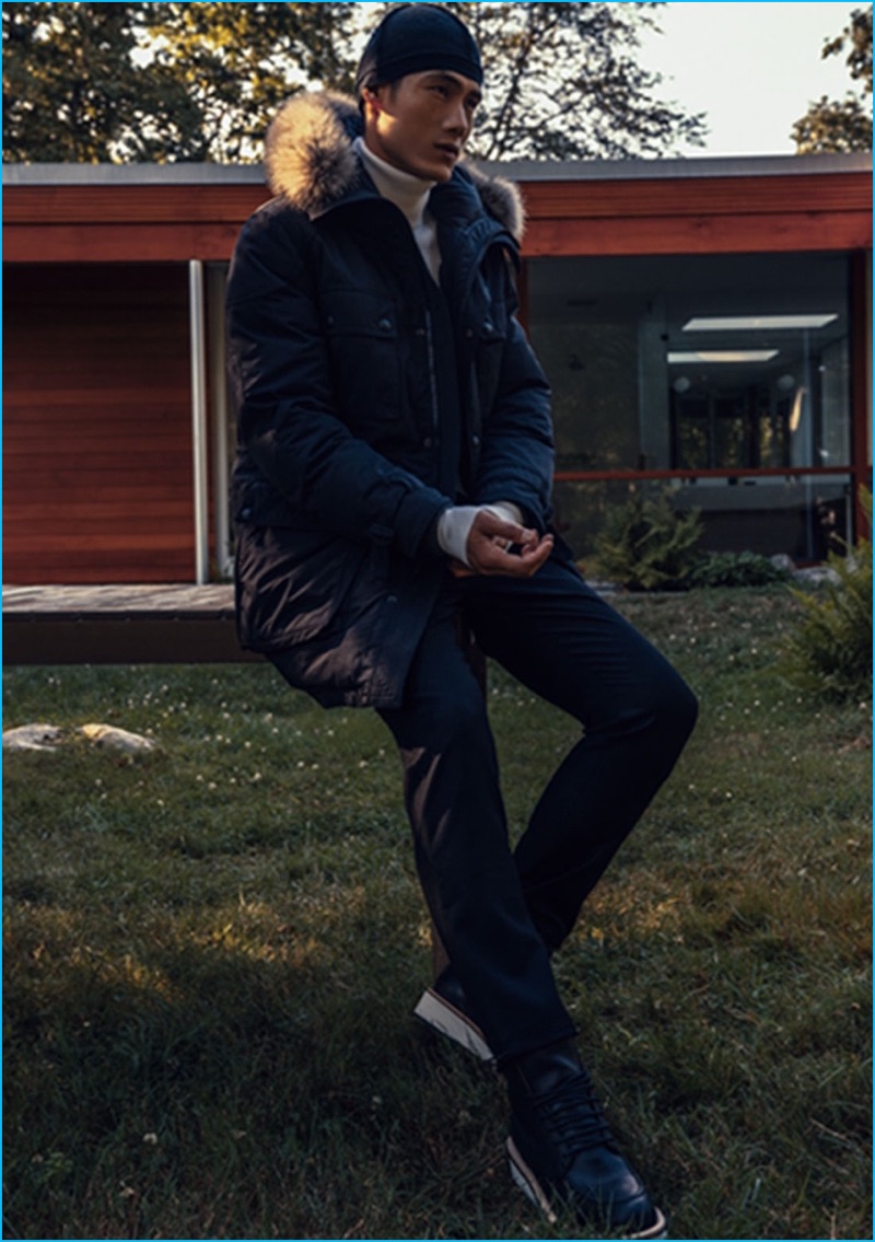 Model Hao Yun Xiang sports a Belstaff fur-trimmed parka with a turtleneck sweater by Jil Sander. Hao also wears Maison Margiela trousers, Givenchy leather lace-up boots, and a Balenciaga beanie.