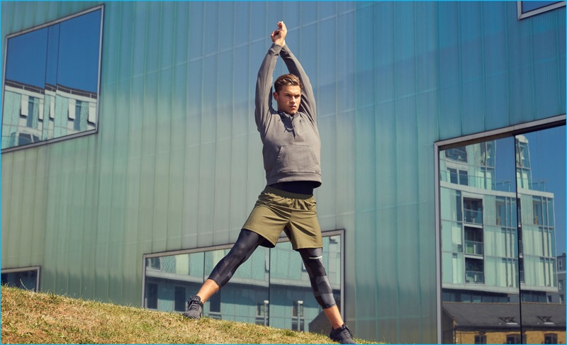 Zachary Grenenger stretches in a hooded sweatshirt by The Upside with Every Second Counts performance shorts. The Australian model also sports geo camouflage leggings from The Upside with Brandblack sneakers.