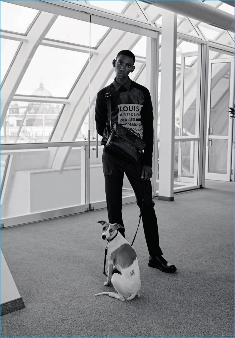 Model Myles Dominique goes semi-casual in a Louis Vuitton sweatshirt and trousers with a choice bag.