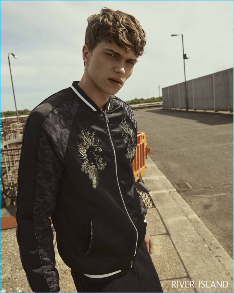 Jake Love rocks a black embroidered satin bomber jacket from River Island.