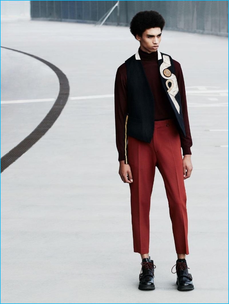 Standing tall, Sol Goss wears a Dries Van Noten vest, Oscar Jacobson sweater, CMMN SWDN trousers, and Dior Homme shoes.