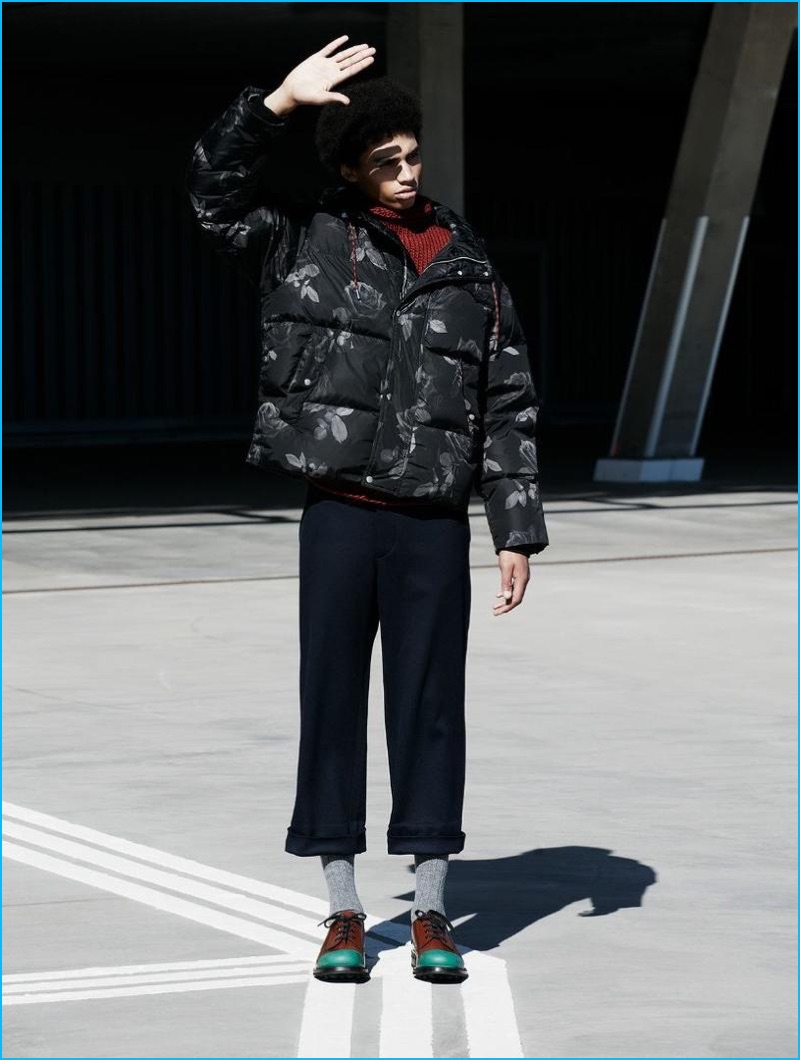 Sol Goss sports a Dior Homme rose print parka with a CMMN SWDN knit. The leading model also dons Prada cropped trousers and color-blocked dress shoes.