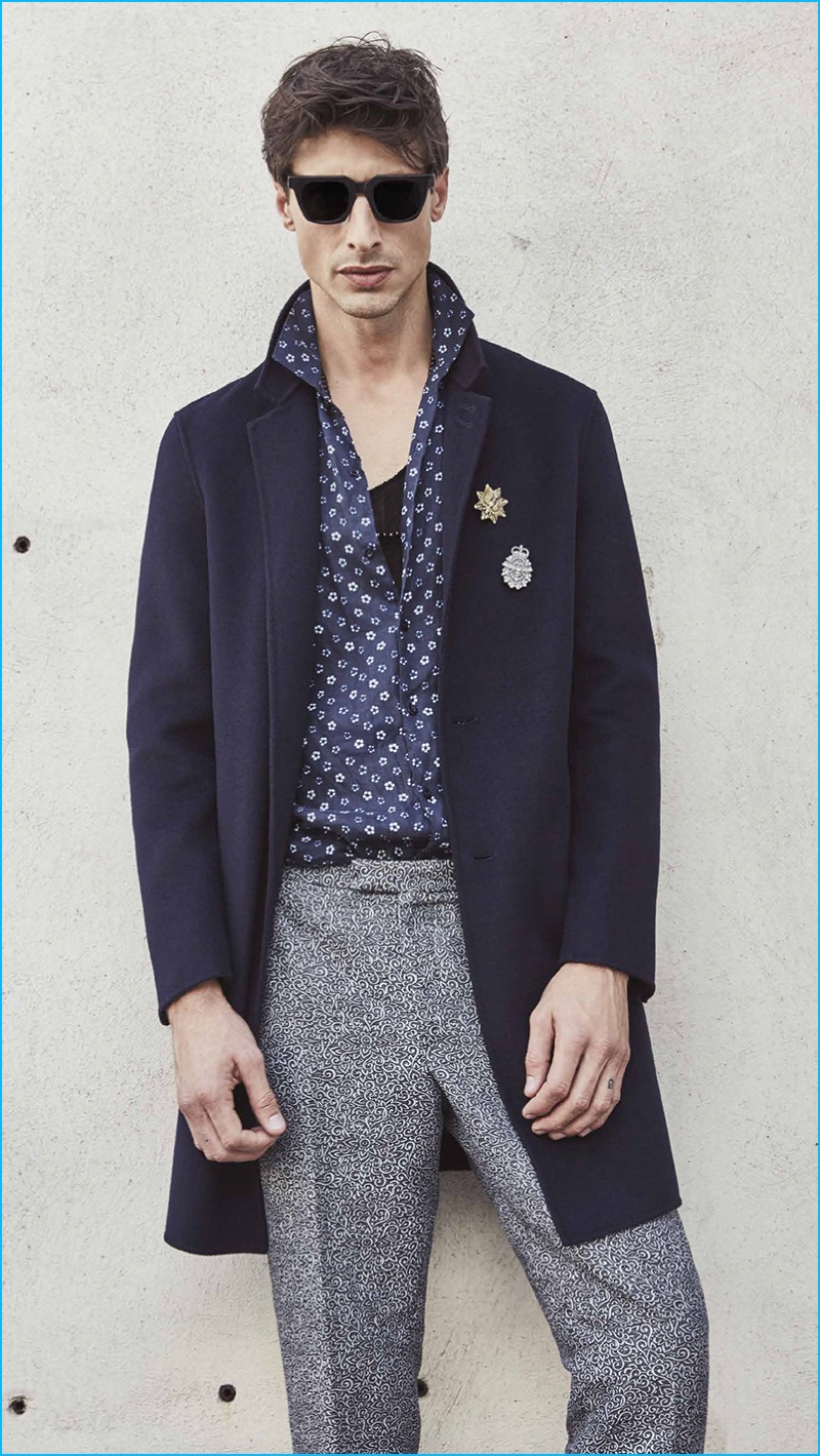 A cool vision, Jonas Mason sports a navy coat with a patterned shirt and trousers by The Kooples.