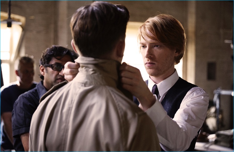 Domhnall Gleeson portrays Thomas Burberry fitting one of his signature trench coats.