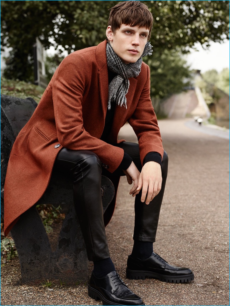 Callum Ward sports a single-breasted coat with a cashmere sweater, faux leather pants, and bluchers from Zara Man.