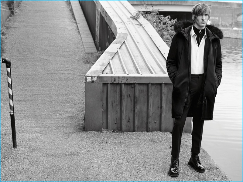 Model Tim Dibble wears an oversized parka, printed shirt, technical suit trousers, and black boots from Zara Man.