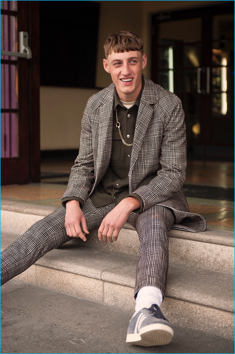 All smiles, Aubrey wears a coat and pants by COS with a Kenzo x H&M shirt, River Island t-shirt, Topman necklace, Calzedonia socks, and Adidas Gazelle sneakers.