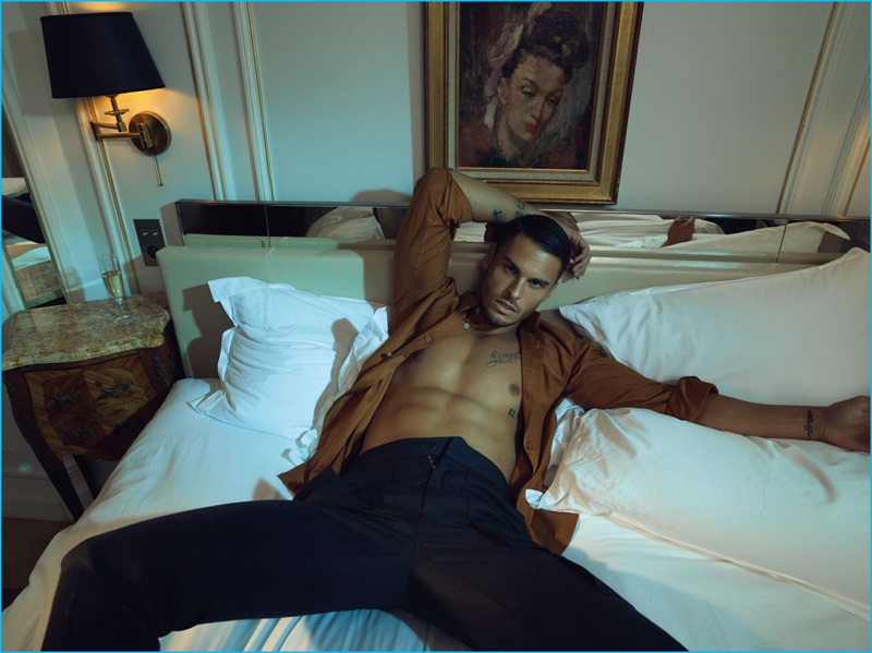 Laying in bed with an open shirt, revealing his six-pack, Baptiste Giabiconi wears Monlada Homme and Louis Vuitton.