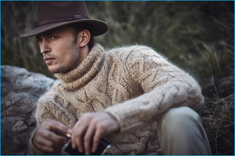 Starring in an editorial for Gentleman's Journal, Harvey Haydon dons a Michael Kors turtleneck sweater with a Barbour hat.