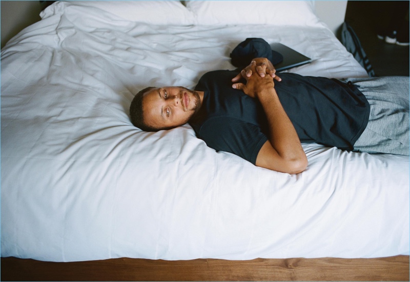 Relaxing on a bed, Stephen Curry sports an Under Armour x Tim Coppens t-shirt with Under Armour joggers.