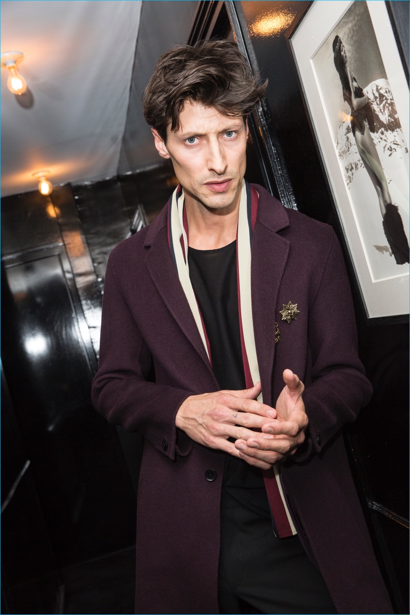 Model Jonas Mason dons a wool coat with badges from The Kooples' Moonlight capsule collection.