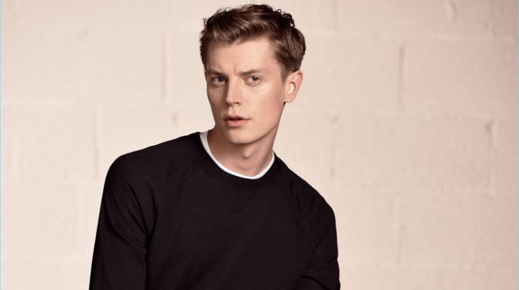 Janis Ancens sports a crewneck sweater with slim-fit jeans and white sneakers by BOSS Hugo Boss.