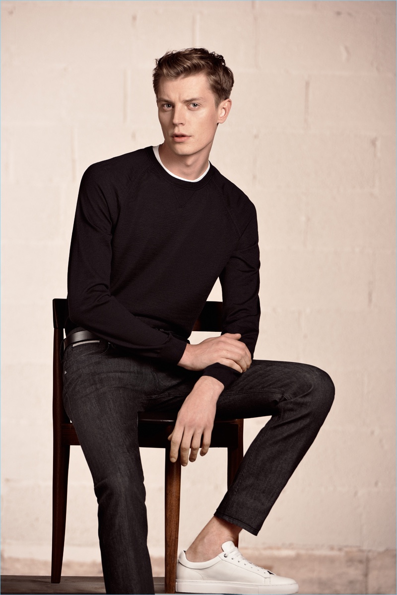 Janis Ancens sports a crewneck sweater with slim-fit jeans and white sneakers by BOSS Hugo Boss.