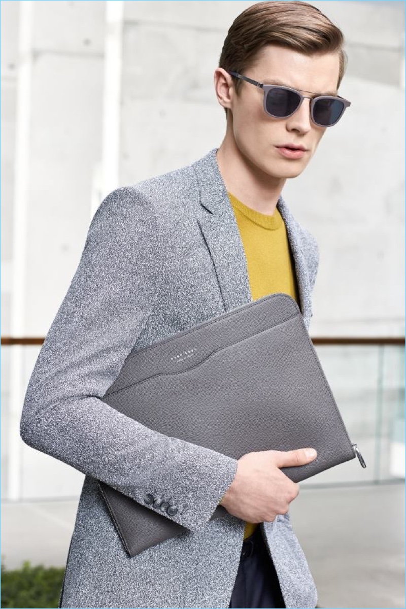 Donning grey shades, Janis Ancens is a sleek vision in a BOSS sportcoat and yellow sweater. The Latvian model also carries a leather portfolio.