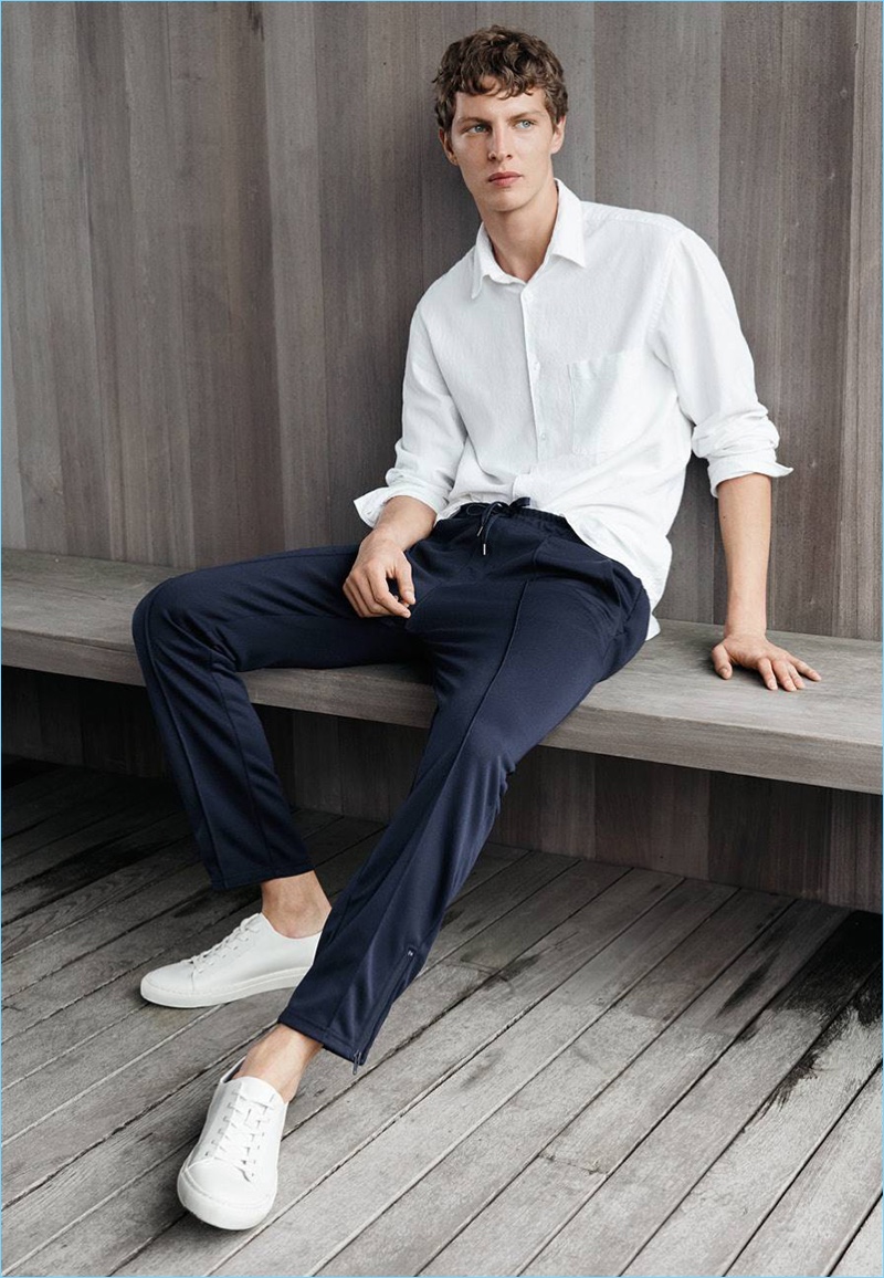 Model Tim Schuhmacher relaxes in H&M's linen-blend shirt, joggers, and white sneakers.